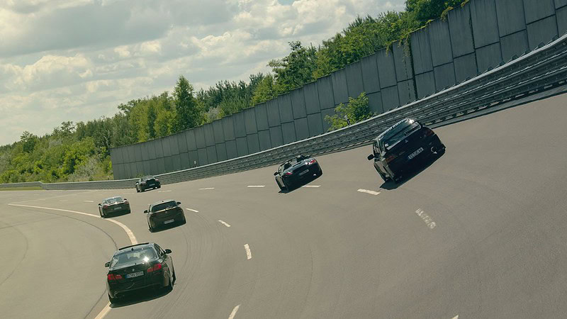 Sechs schwarze Autos fahren auf einer Rennstrecke.