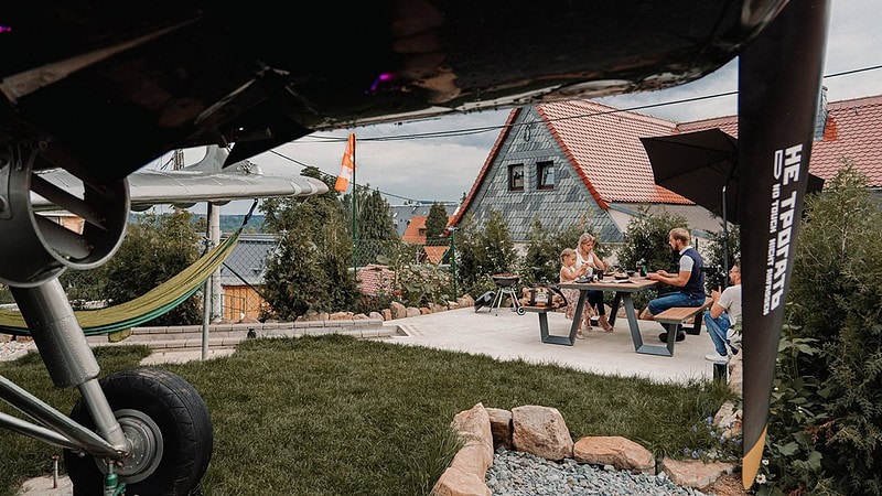 Blick unter der Antonov durch, auf eine Familie die an einem Picknicktisch isst.