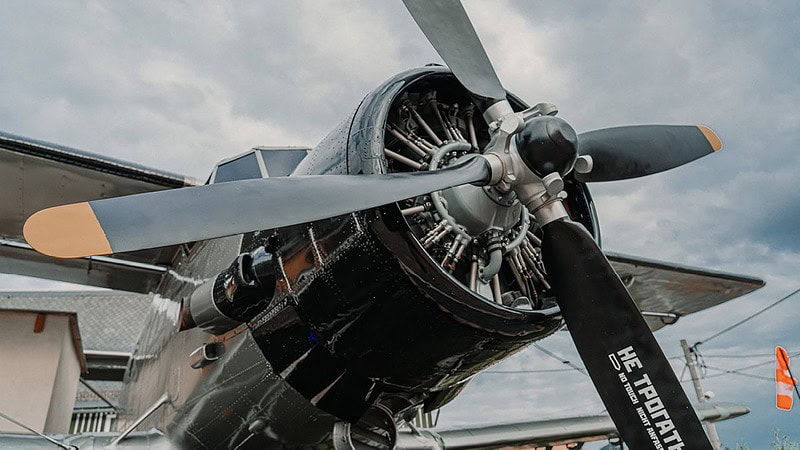 Nahaufnahme von Propeller und radialem Motor der Antonov, im Hintergrund flattert eine windsack im Wind.