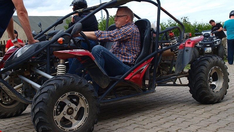 Ein älterer Mann sitzt einem roten Buggy.