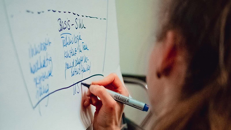 Eine Person schreibt die Zutaten für eine Bowl auf ein Whiteboard auf.