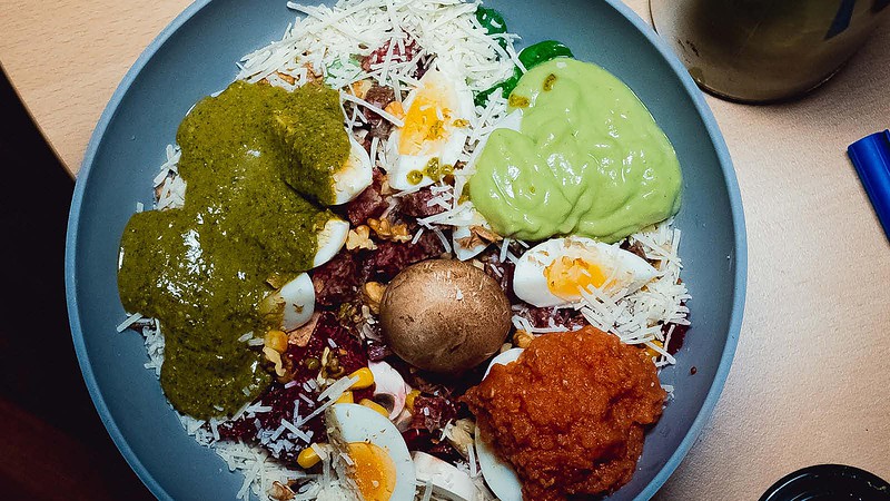 Gemüsesalat mit Eiern, Avocado, Emmer-Reis und würziger Soße, gesundes veganes Gericht.