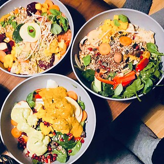 Drei bunte Bowls mit frischem Gemüse, Salat und Ei auf einem Holztisch von oben fotografiert.