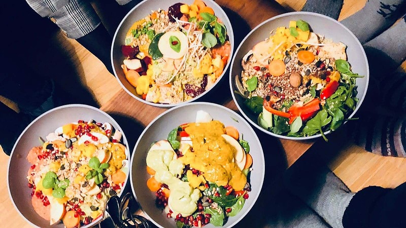 Drei bunte Bowls mit frischem Gemüse, Salat und Ei auf einem Holztisch von oben fotografiert.