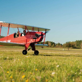 Zwei Personen fliegen mit einem roten Doppeldecker los. Rundflug Grossenhain.