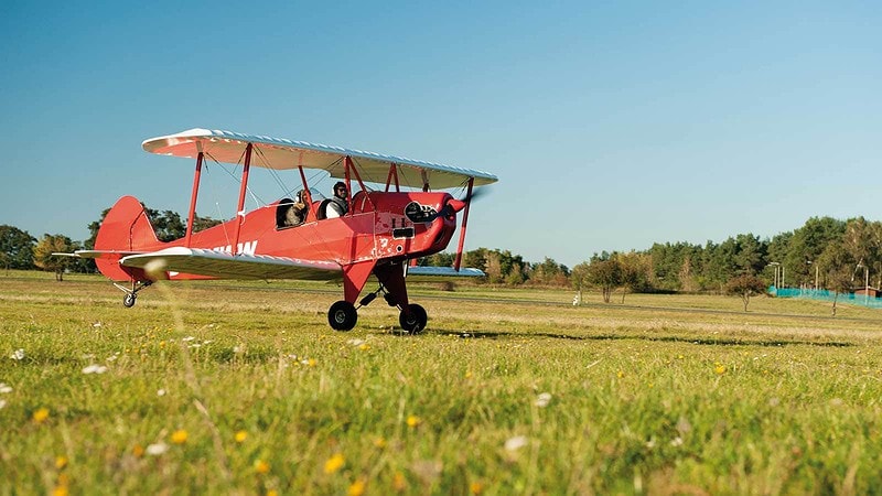 Zwei Personen fliegen mit einem roten Doppeldecker los. Rundflug Grossenhain.
