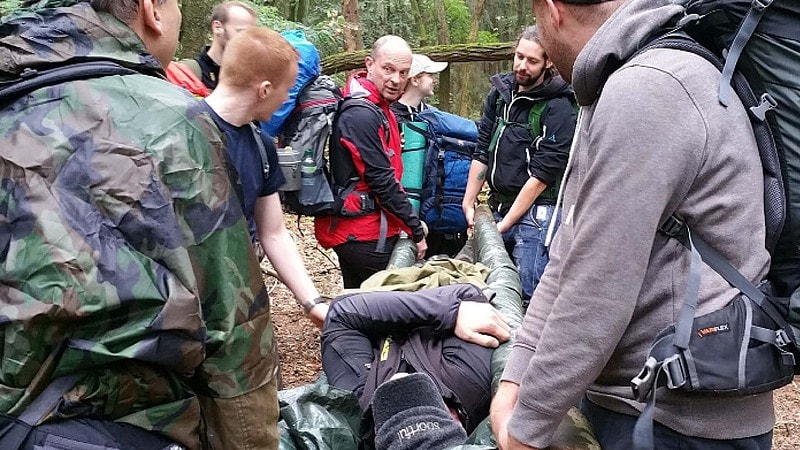 Eine Gruppe bei einem Survival Camp, die extrem Situation simulieren, bei der eine Person verletzt ist und getragen werden muss.