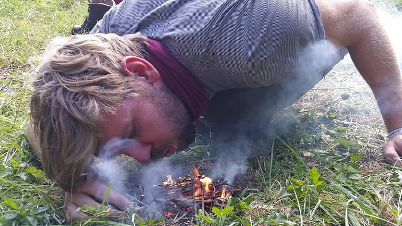 Ein Mann versucht mit ein Feuer zu entfachen.