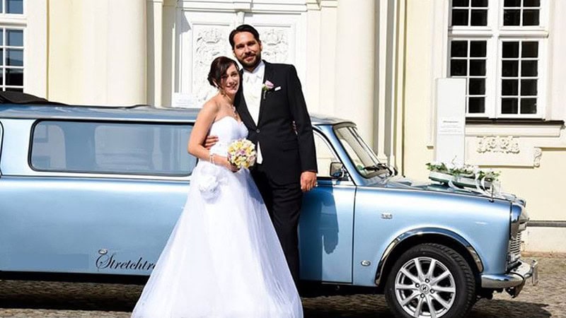 Ein frisch verheiratetes Paar vor einer Trabant-Stretchlimousine.