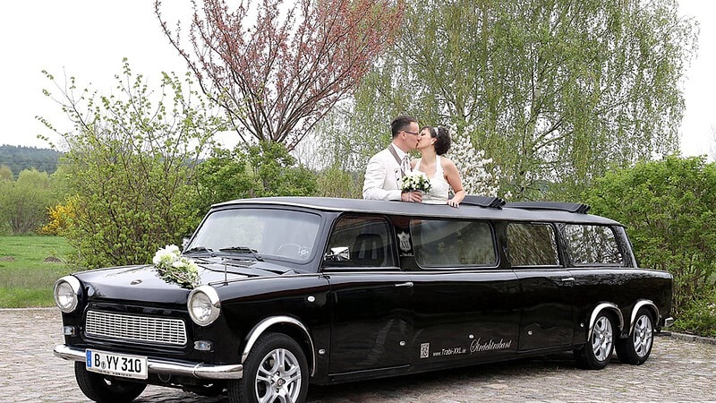 Brautpaar schaut aus dem Verdeck der Hochzeitstrabant-Stretchlimousine und küsst sich.