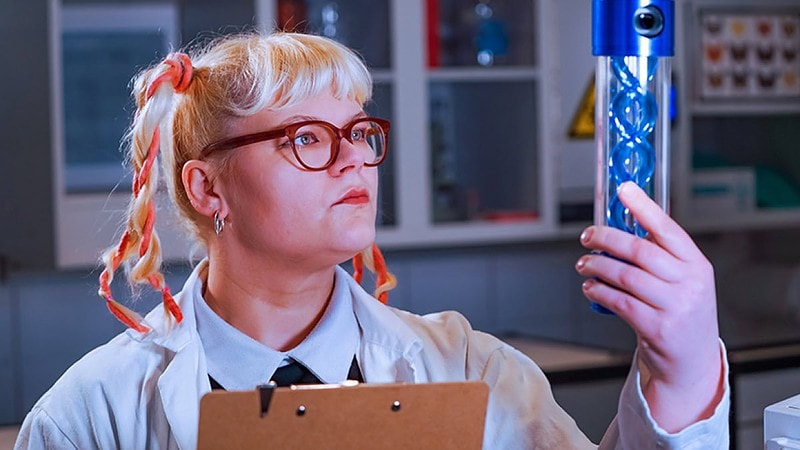 Eine Frau schaut auf ein großes Reagenzglas mit einer Doppelhelix.