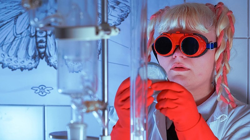 Eine Frau mit einer Schutzbrille bei einem Experiment.