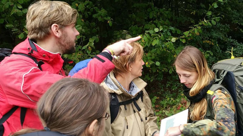 Eine Gruppe Personen beim Kartenlesen auf einem Survival Wochenende in Brandenburg.