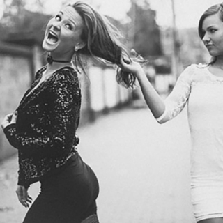 Zwei Frauen in schillerndem Outfit posieren bei einem Lifestyle-Fotoshooting, eine zieht die andere dynamisch zur Seite.