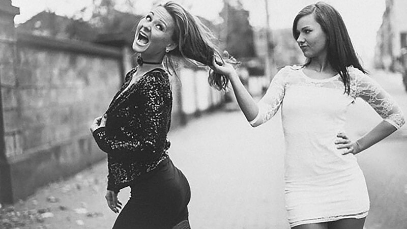 Zwei Frauen in schillerndem Outfit posieren bei einem Lifestyle-Fotoshooting, eine zieht die andere dynamisch zur Seite.