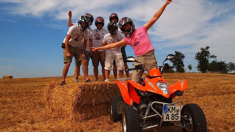 Die Teilnehmer einer Quad Tour posieren vor einem Quad für ein Bild.