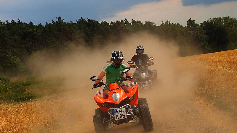 Zwei Männer fahren auf ihren Quads über Schotterwege.