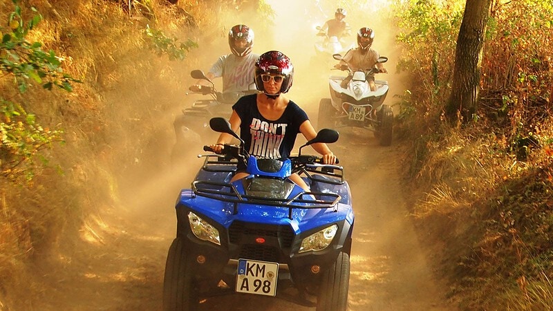 Eine Frau fährt bei der Quad Tour durch den Wald vor. Hinter ihr folgen drei Männer auf Quads.