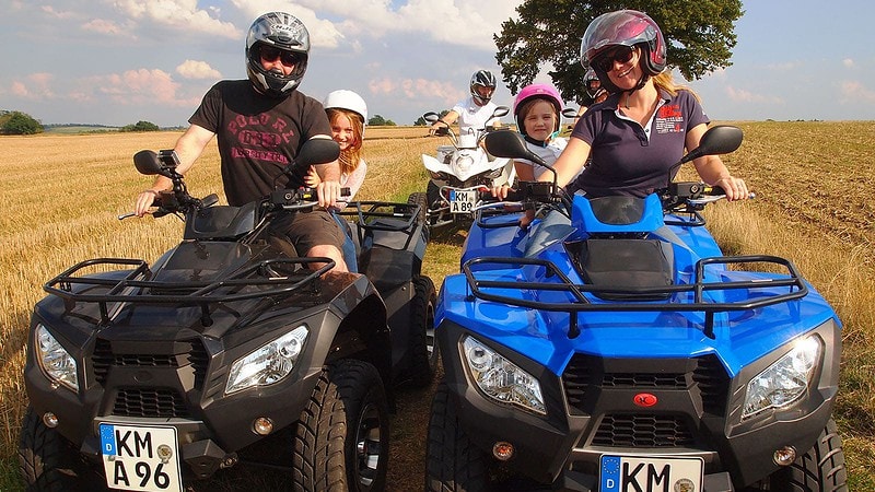 Eine Frau und ein Mann mit ihrem beiden Kindern als Beifahrer auf den Quads.