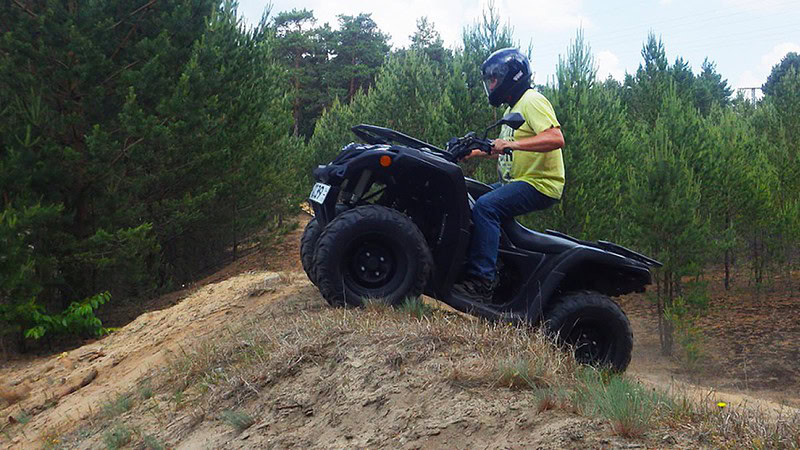 Ein Mann fährt mit einem Quad einen Hügel hoch.