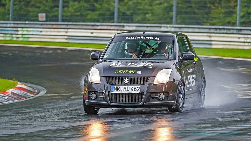 Suzuki Sportwagen bei einem Rennen auf einer nassen Rennstrecke.