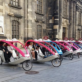 Acht Rikschas stehen nebeneinander in einer Reihe in Dresden bereit für eine Tour.
