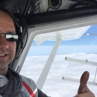 Ein Mann zeigt mit seinem linken Daumen beim Rundflug über die Oberlausitz, dass ihm der Flug gefällt.