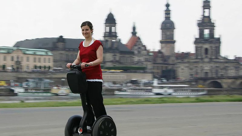 Eine Frau fährt auf einem Segway am Elbufer in Dresden.