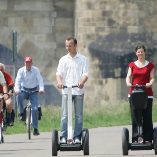 Drei Personen fahren jeweils auf einem Segway der Elbe entlang in Dresden.