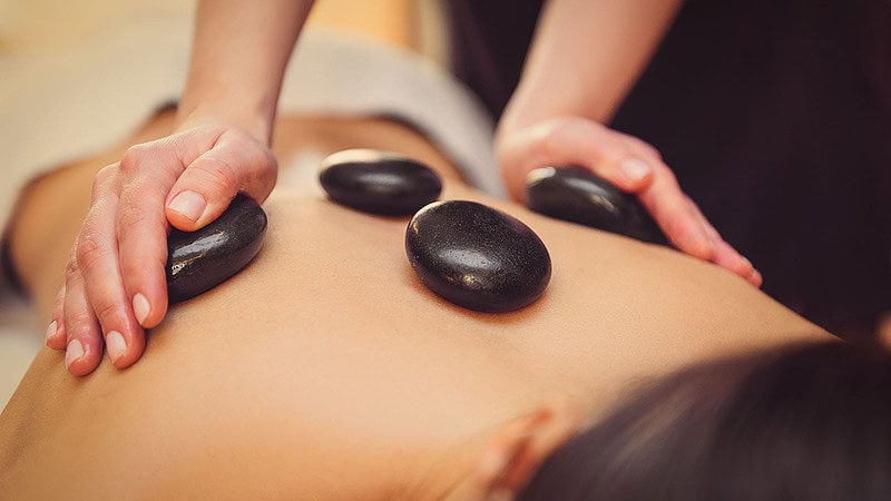 Eine Frau deren Rücken mit Hot Stones massiert wird.