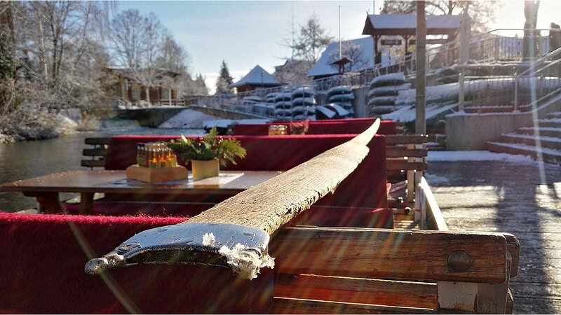 Winterlicher Spreewaldkahn mit roten Bänken und Frost, vorbeifahrende Boote vor schneebedeckten Häusern.