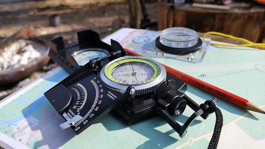 Kompass mit Survival Zubehör auf einer Landkarte. Survival Kurs