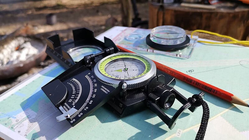 Kompass mit Survival Zubehör auf einer Landkarte. Survival Kurs