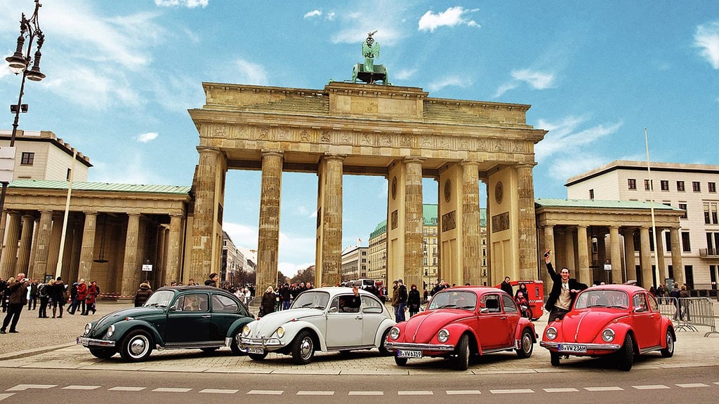 Vier VW Käfer stehen vor dem Brandenburger Tor.