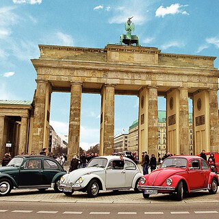 Vier VW Käfer stehen vor dem Brandenburger Tor.