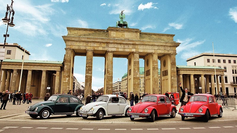 Vier VW Käfer stehen vor dem Brandenburger Tor.