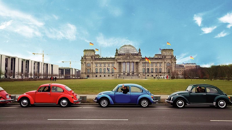Vier VW Käfer parken in einer Reihe vor dem Bundestag in Berlin.