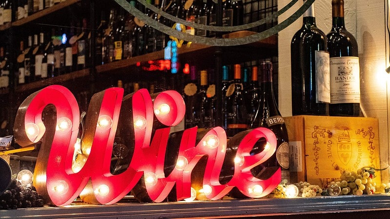 Ein roter Wine-Schild, im Hintergrund verschiedene Weinsorte