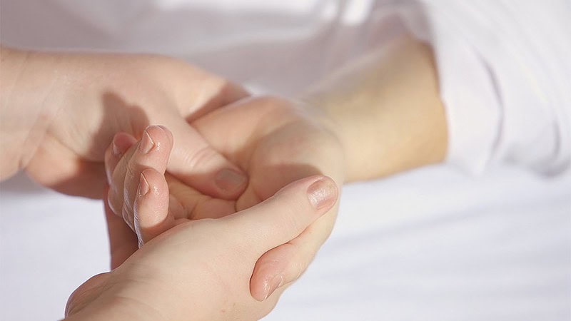 Eine Person massiert einer anderen Person sanft die linke Hand