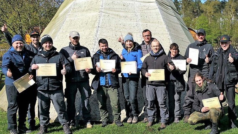 Eine Gruppe Personen zeigt Stolz ihr Zertifikat nach dem Survival Wochenende.