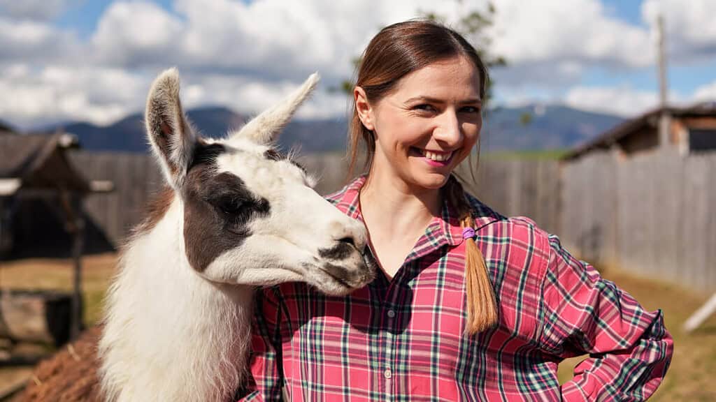 Eine Frau lächelt mit dem Lama an ihrer Seite.