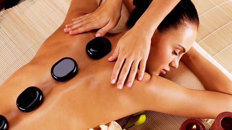 Eine Frau liegt auf einem Massagebett mit heißen Steinen auf ihrem Rücken