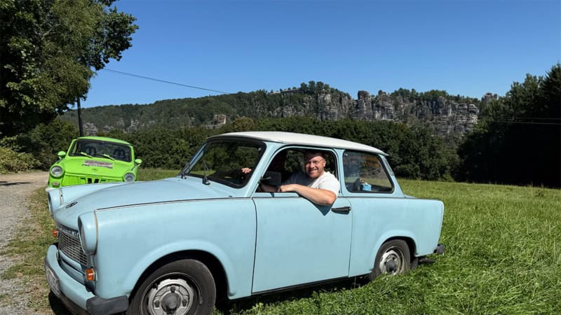 Mann schaut aus blauem Trabant