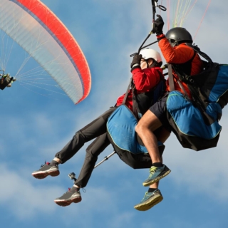 2 Personen fliegen mit einem Gleitschirm, Blick von unten, Himmel und Wolken im Hintergrund