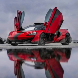 ein roter McLaren mit nach oben geöffneter Tür, in einer regnerischen Umgebung
