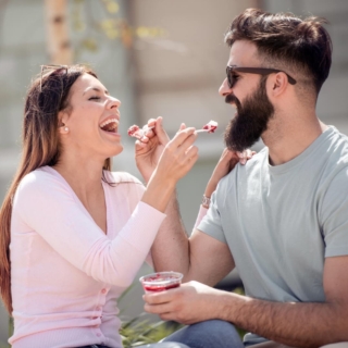 Eine Frau und ein Mann genießen gemeinsam ein Dessert aus einem Becher.