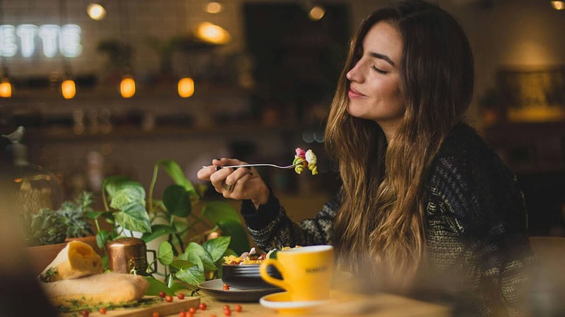 eine junge Frau sitzt in einem Restaurant und genießt ihr Essen