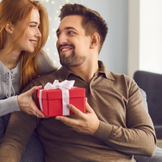 Ein Mann bekommt von seiner Frau ein Geschenk überreicht.