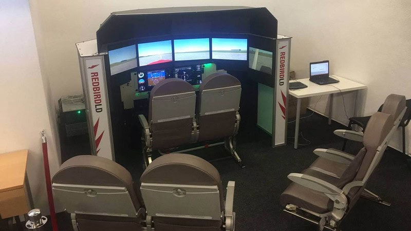 Flugzeugsimulator-Raum mit Zuschauersitzen.