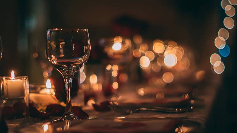 Ein geeckter Tisch mit angezündeten Kerzen bei einem Candle Light Dinner.